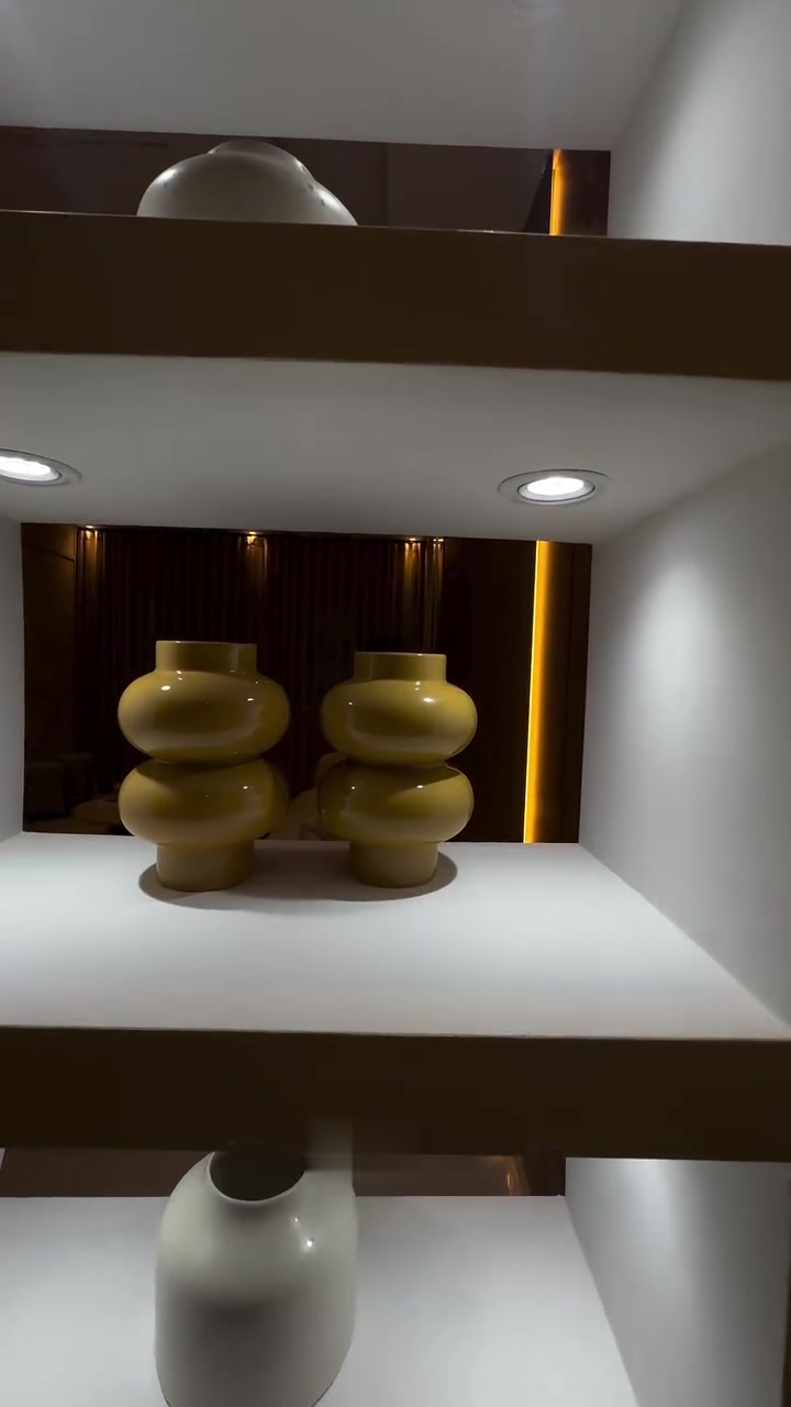 Mueble de nichos blancos con focos y jarrones decorativos