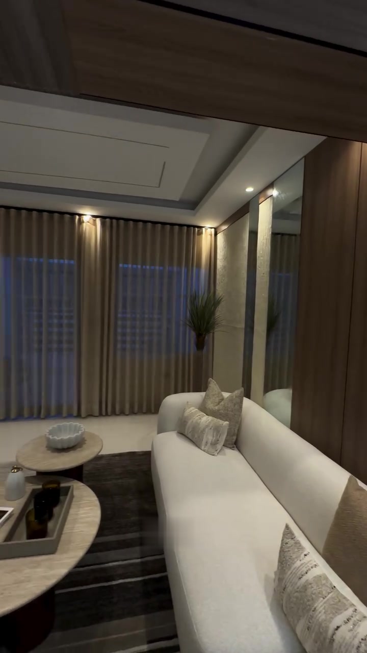 Sala con cortinas de piso a techo, espejos y focos empotrados en el techo