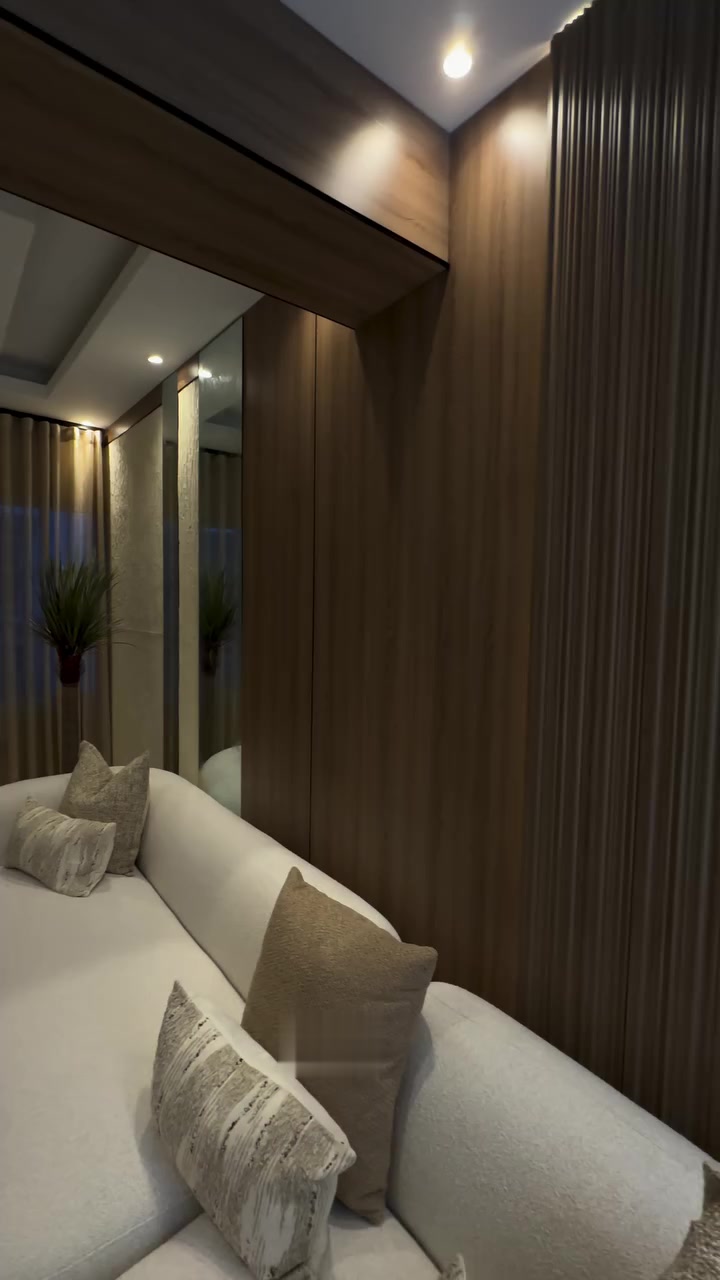 Sofá blanco curvo junto a panel de madera y techo con luz