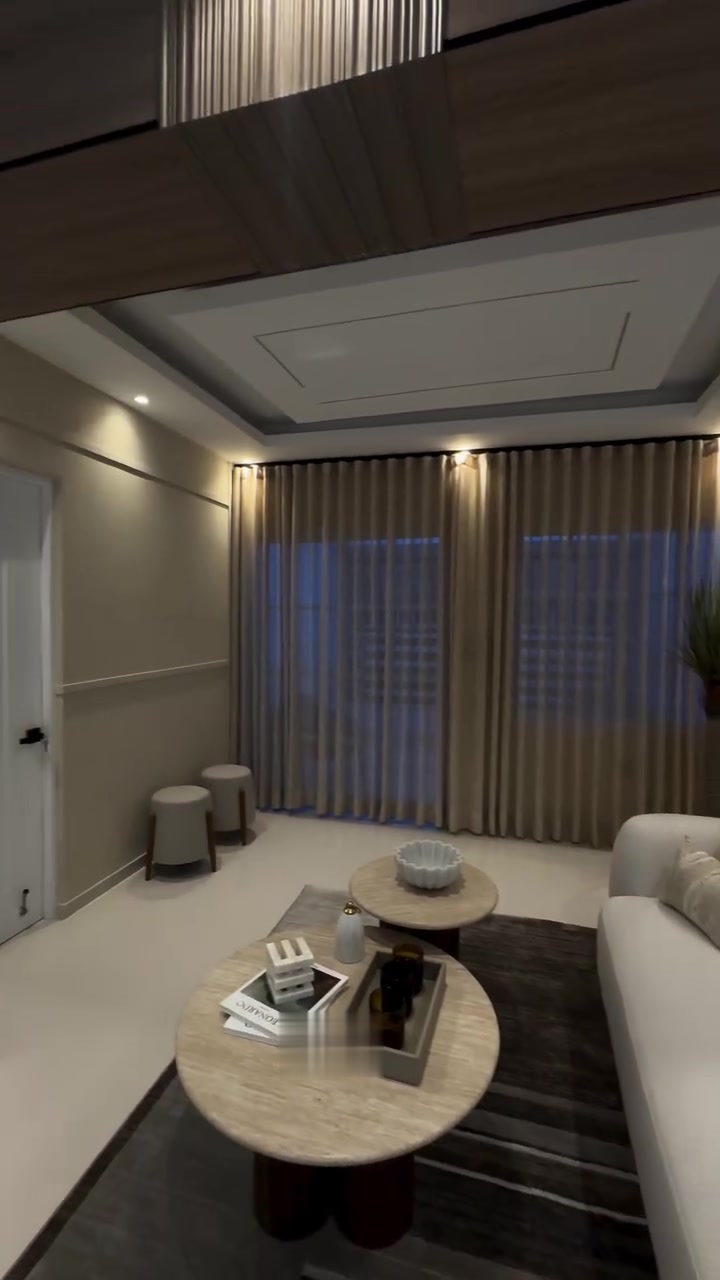 Sala con techo en bandeja de sheetrock, luz perimetral cálida y cortinas de piso a techo